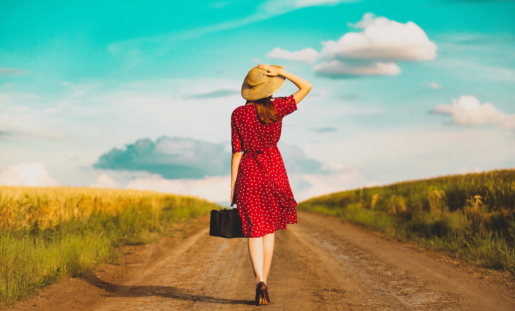 woman with travel siutcase on countryside road